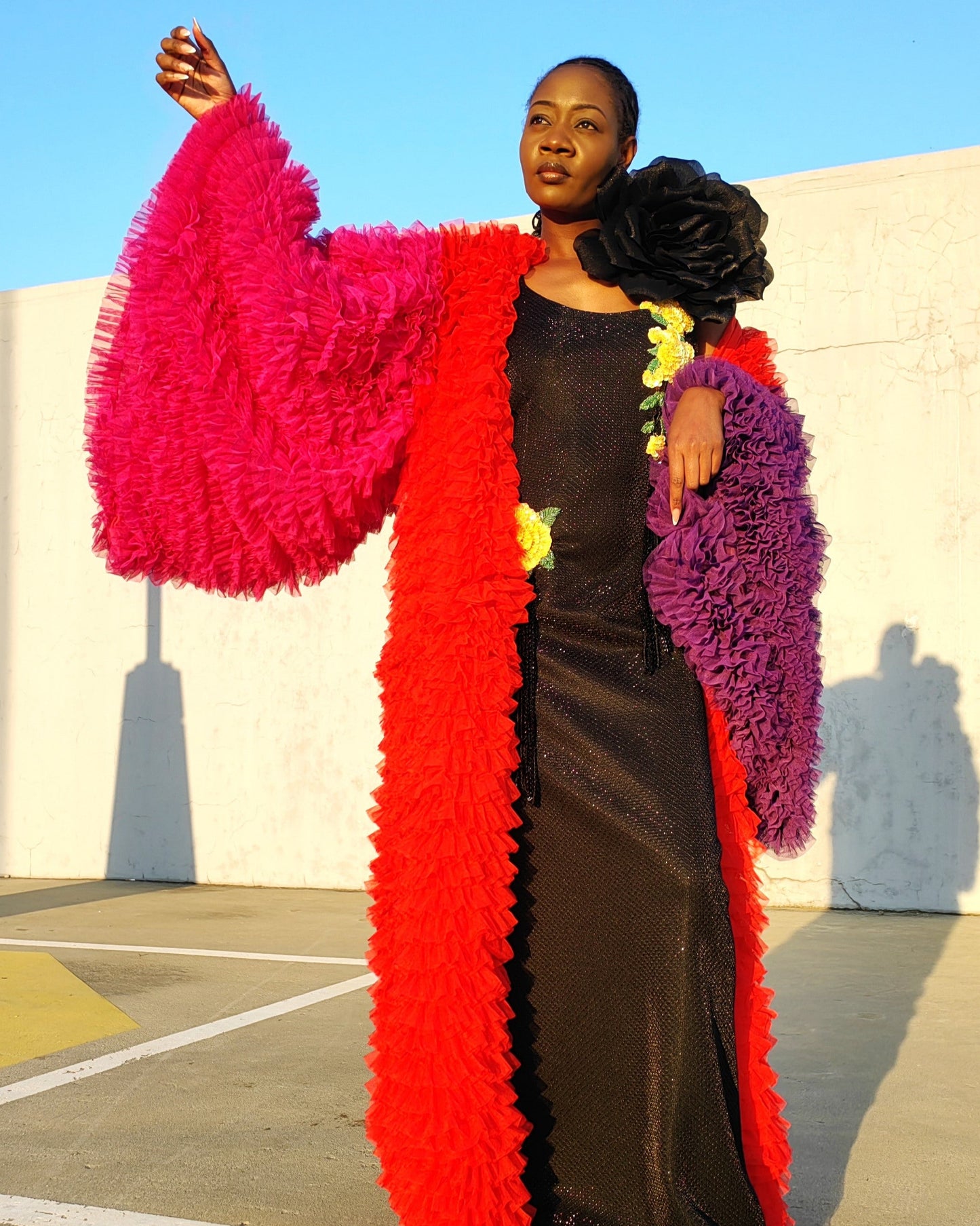 Person wearing a colorful, fluffy coat with a black dress underneath, standing outdoors.