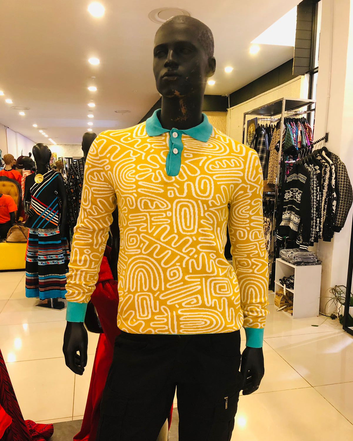 Mannequin wearing a yellow patterned shirt with teal accents in a store setting