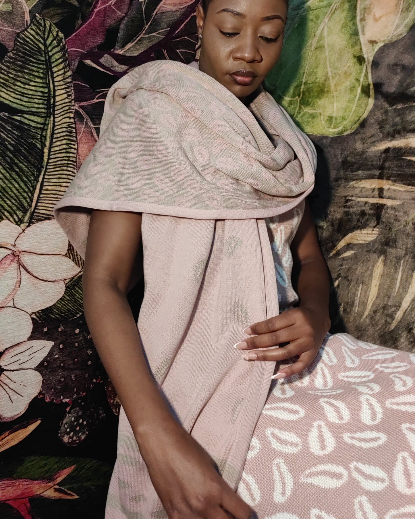 Woman wearing a light pink patterned shawl against a colorful floral and abstract background