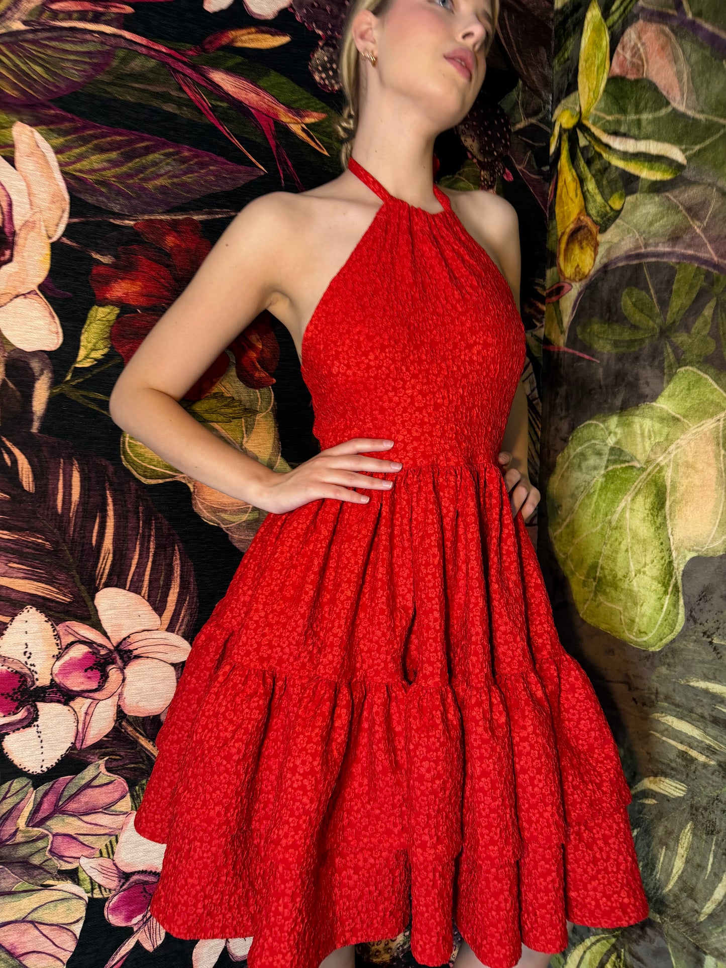 Woman in a red dress lying among floral and leaf patterns