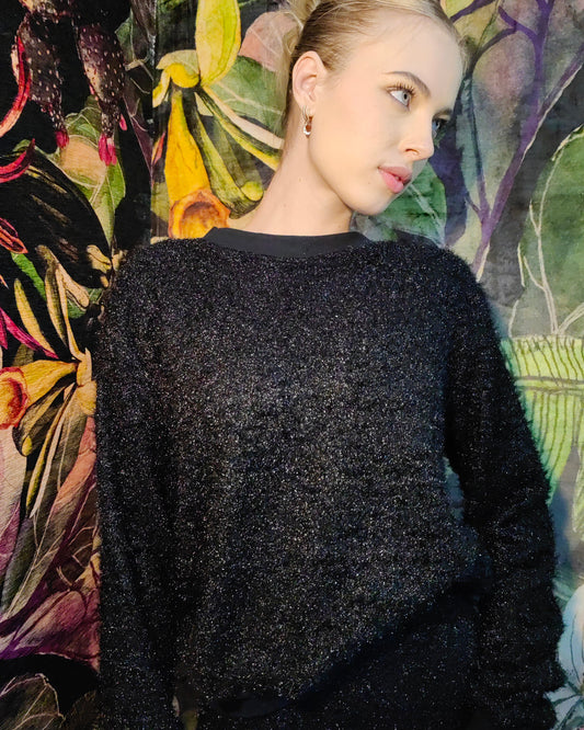 Person wearing a black textured sweater against a colorful floral background