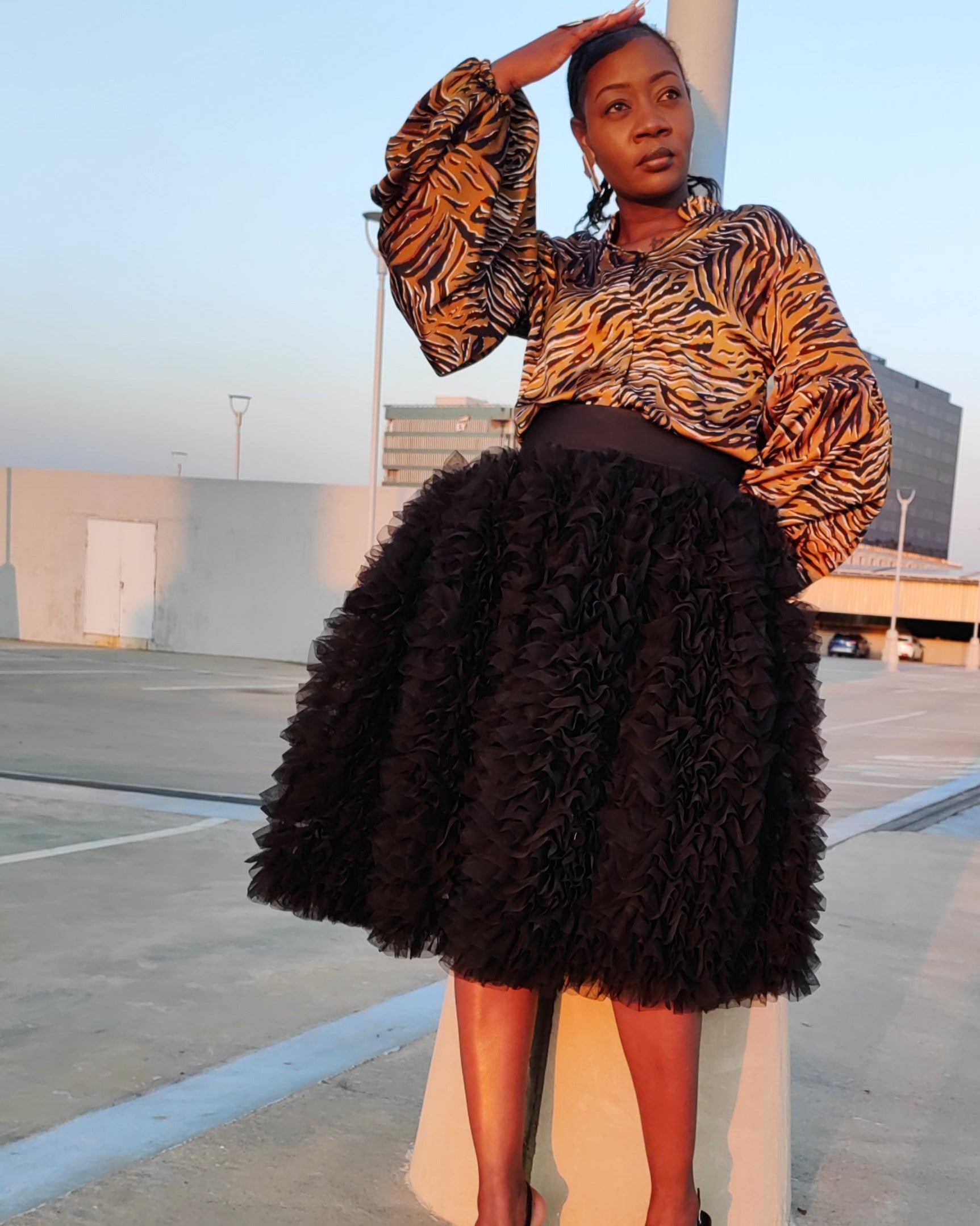 Person wearing a patterned top and black skirt in an outdoor setting