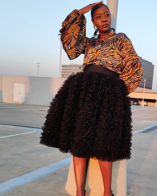 Person wearing a patterned top and black skirt in an outdoor setting