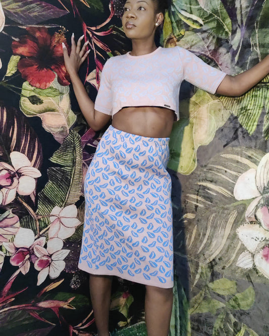 Woman posing in front of a colorful floral and leaf patterned wall.