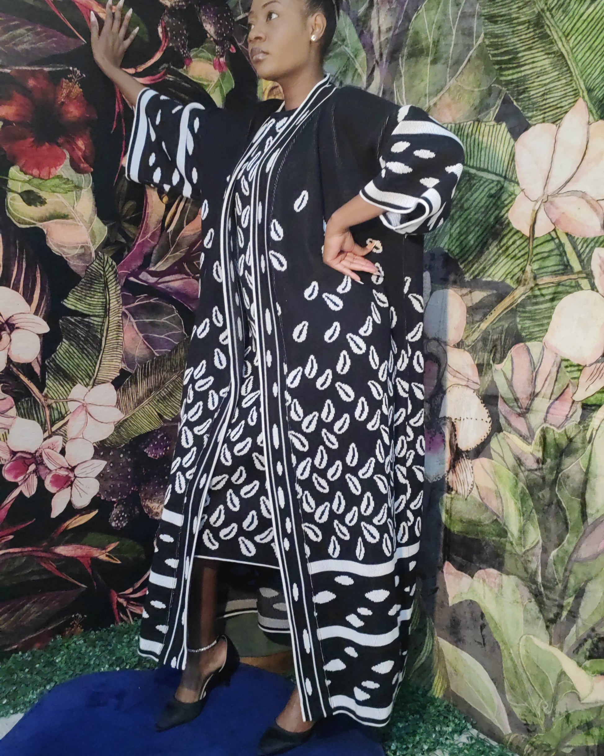 Person wearing a black and white patterned outfit against a floral backdrop