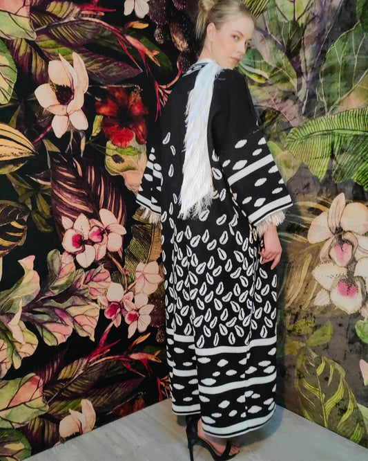 Person wearing a black and white patterned outfit against a floral and leafy background