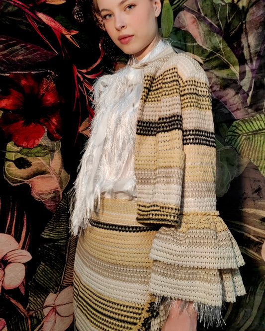 Woman in a patterned outfit standing against a floral and leafy background