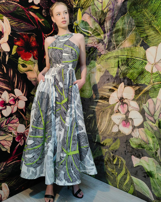 Woman in a patterned dress standing in front of a floral and leaf background