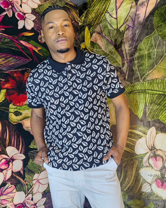 Man wearing a black and white patterned shirt against a colorful floral and leaf background