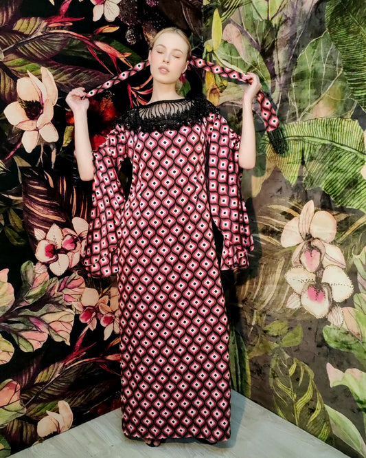Woman wearing a patterned dress against a floral and leafy background