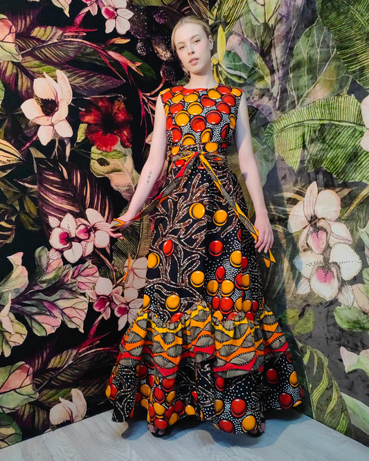 Woman wearing a colorful dress with a floral and leafy background
