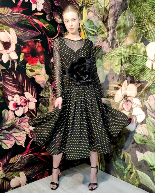 Woman in a black dress with floral and abstract patterns in the background