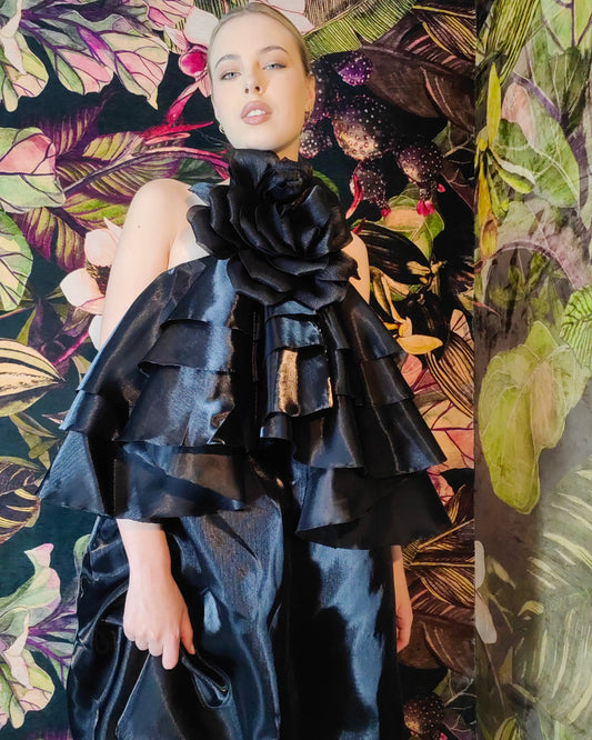 Woman wearing a black, ruffled dress against a colorful, abstract background