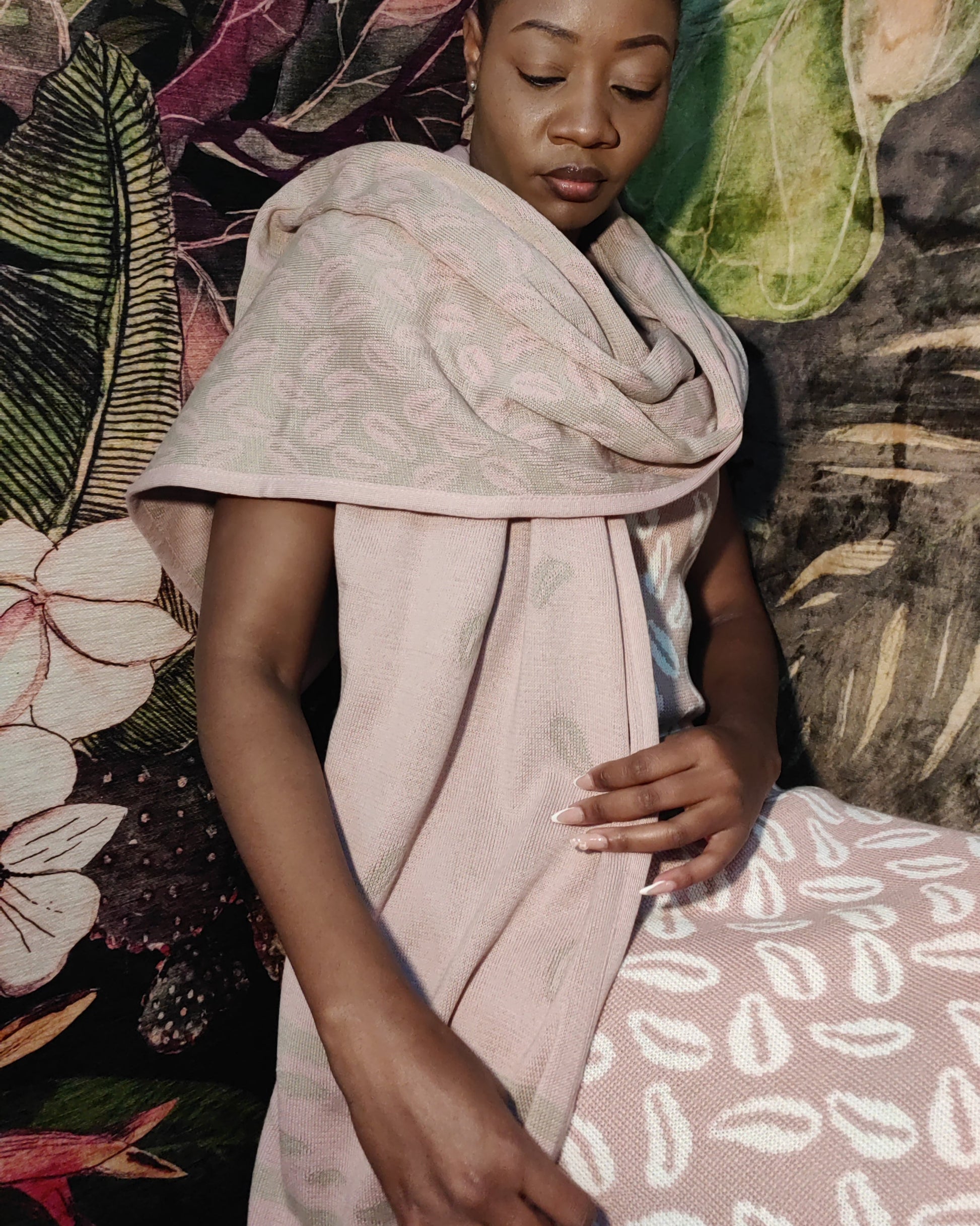 Woman wearing a light pink patterned shawl against a colorful floral and abstract background