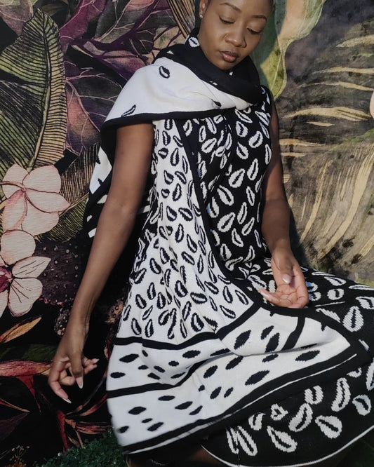 Person wearing a black and white patterned garment against a floral background