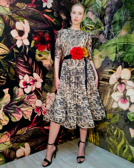Model wearing a patterned dress with a red flower against a floral backdrop