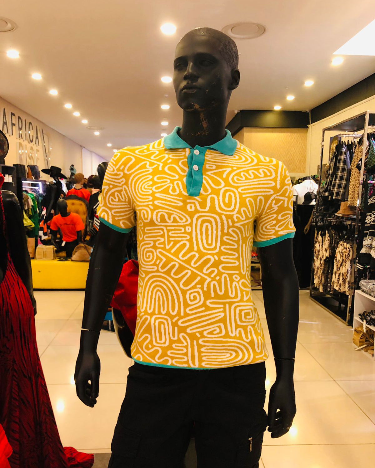 Mannequin wearing a yellow patterned shirt with a blue collar in a store setting