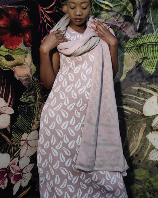 Woman wearing a patterned dress standing against a colorful floral and butterfly backdrop