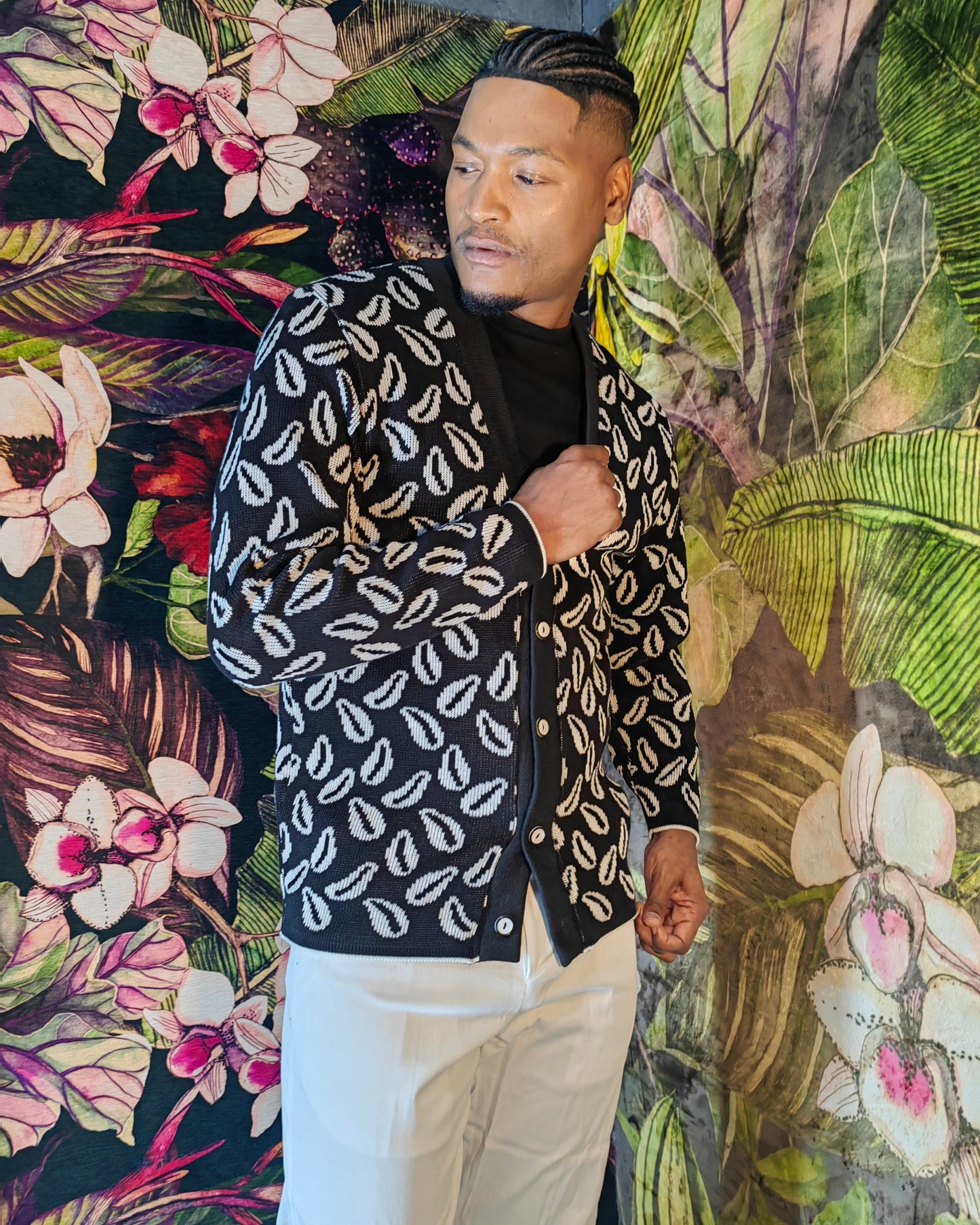 Person wearing a black and white patterned jacket against a colorful floral background