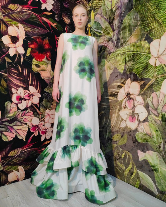 Model wearing a floral dress against a colorful floral and leaf patterned background
