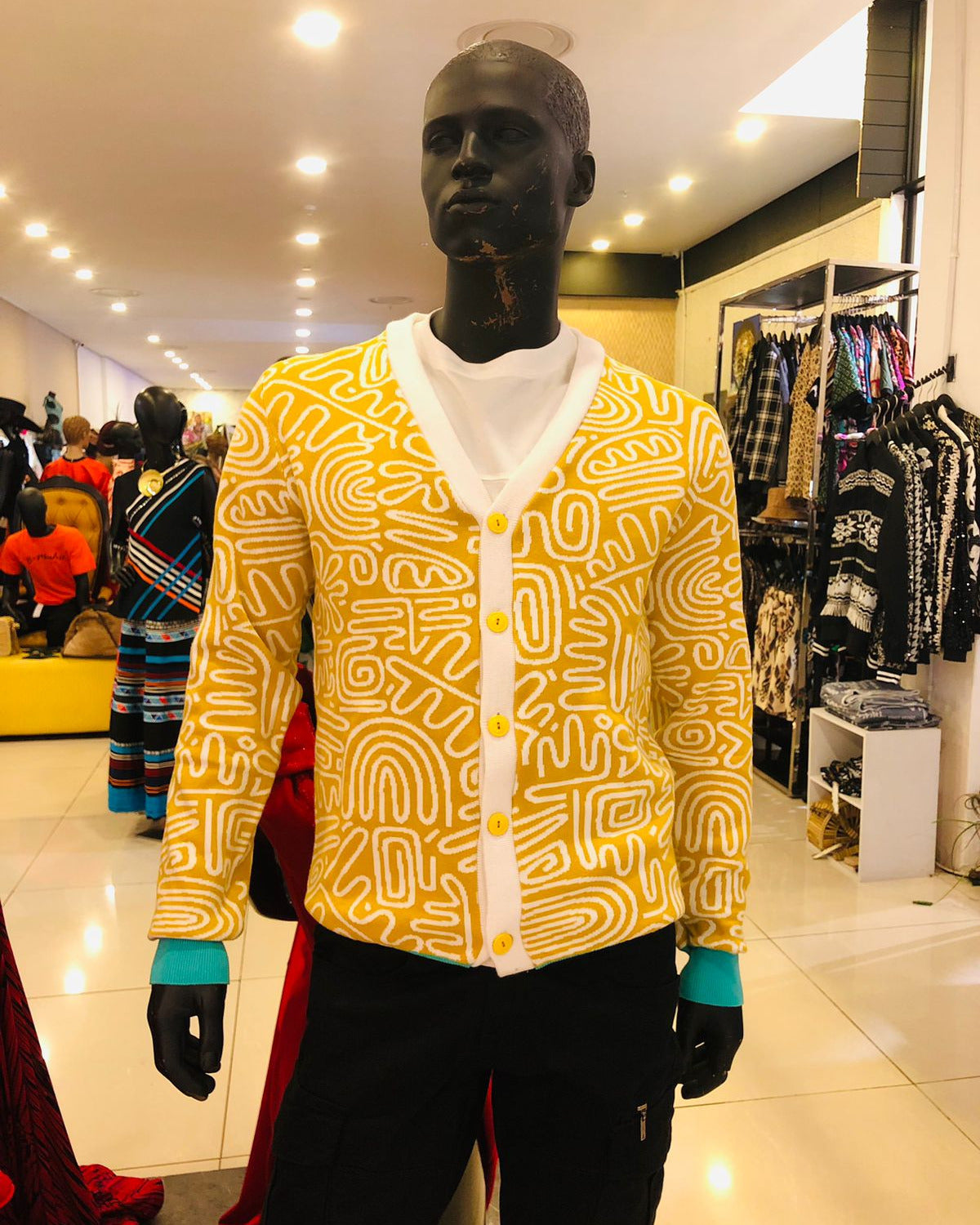 Mannequin wearing a yellow patterned cardigan in a store setting